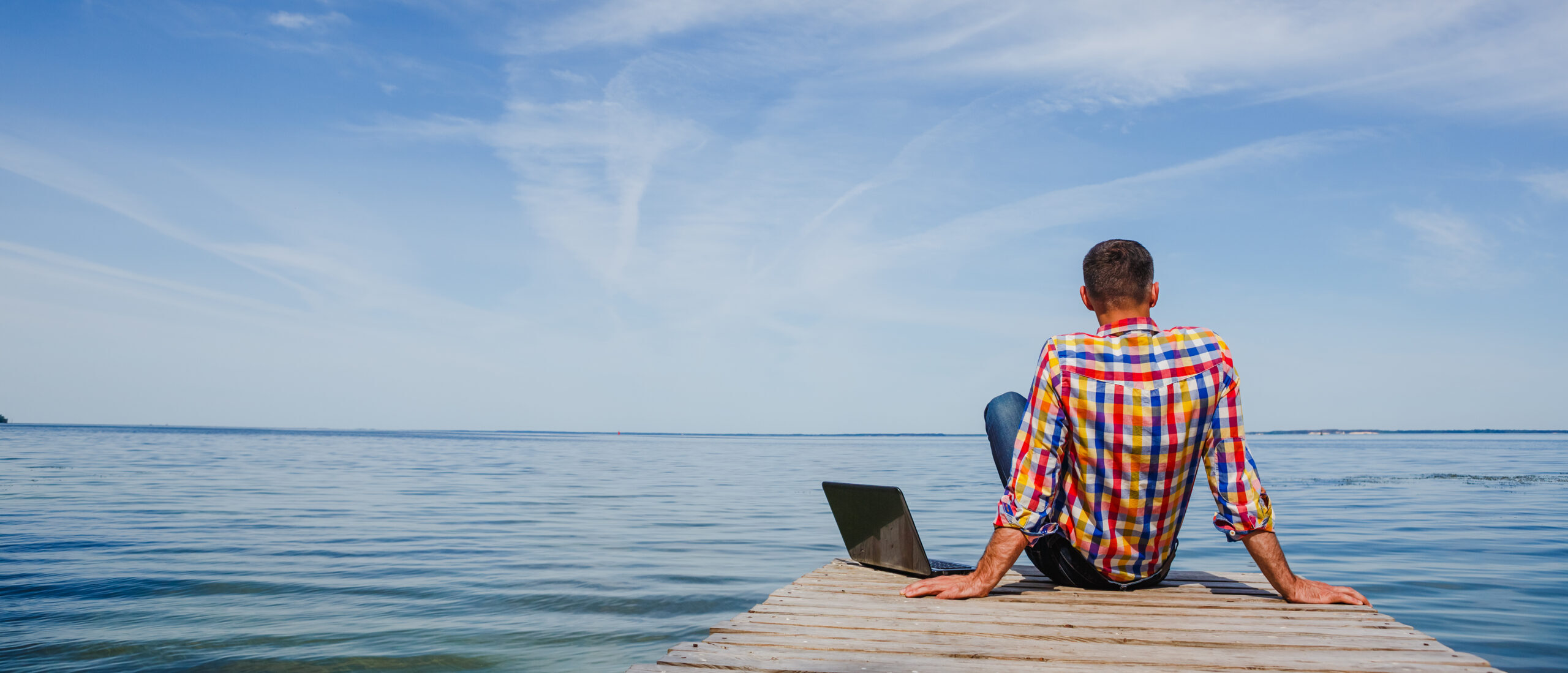 Man sitting with his laptop at the beach