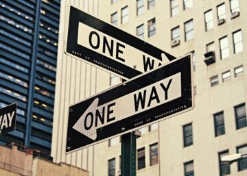 Two one-way road signs pointing in different directions