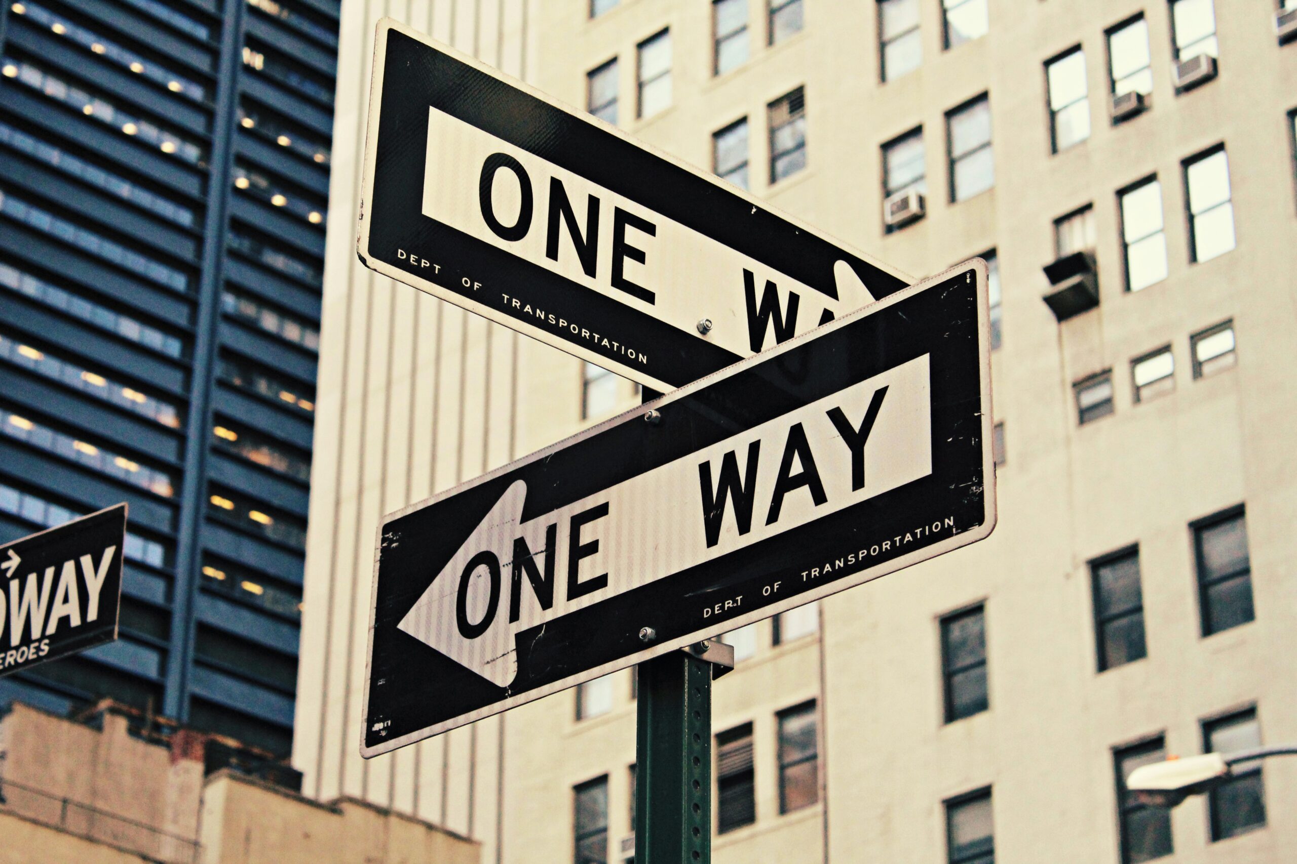 Two one-way road signs pointing in different directions