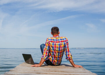 Man sitting with his laptop at the beach