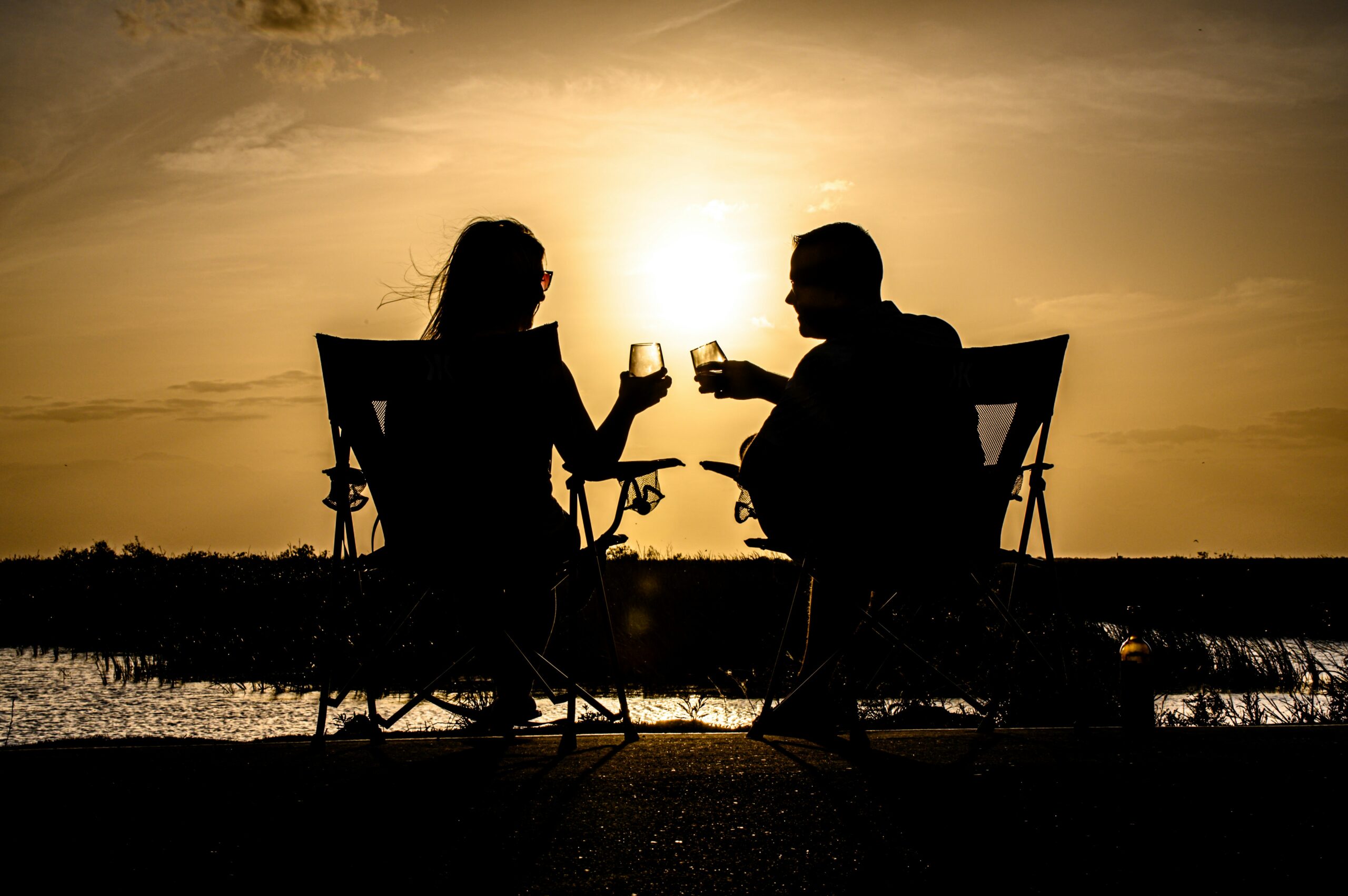 Man and woman sitting on the beach, raising a glass